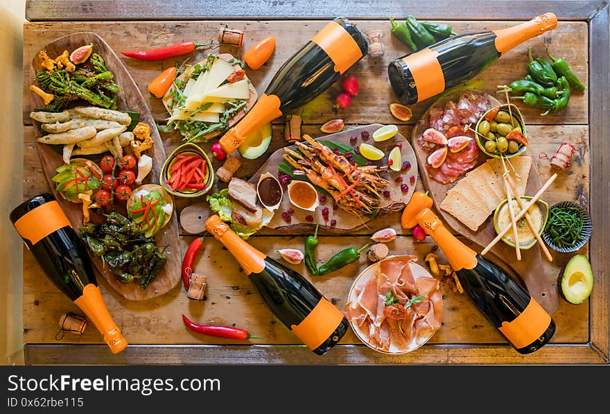 Tapas table full of food and bottles of wine with vegatables, meat and fish