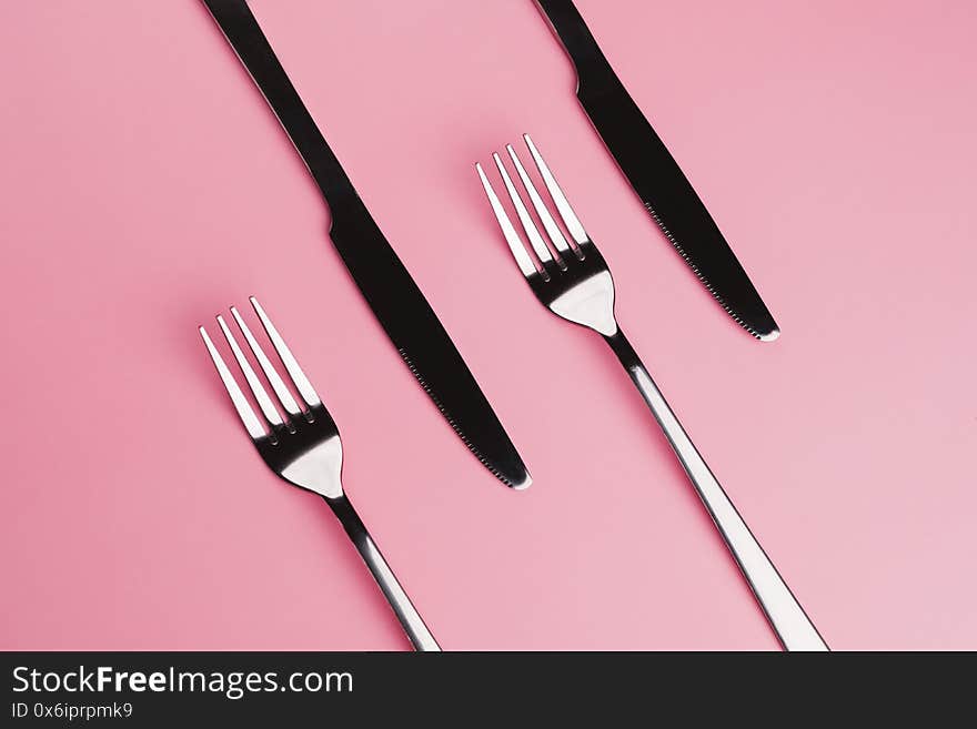 Contrast Forks and knifes isolated on pink background. It`s lunch time concept. Contrast Forks and knifes isolated on pink background. It`s lunch time concept.