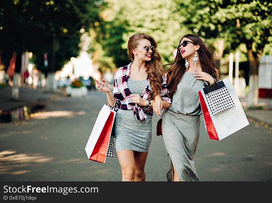 Couple of funny sisters after shopping and big sales happy posing and making face at camera. Stylish brunette and blonde stick out and showing peace sign by fingers, having fun together. Summertime. Couple of funny sisters after shopping and big sales happy posing and making face at camera. Stylish brunette and blonde stick out and showing peace sign by fingers, having fun together. Summertime.