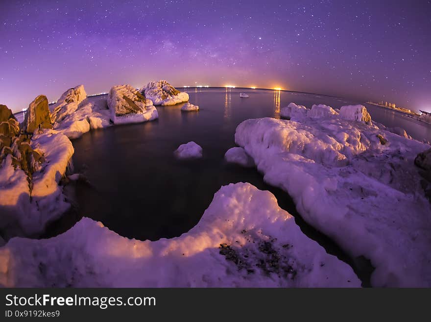 On winter nights, snow and ice cover the rocks by the sea