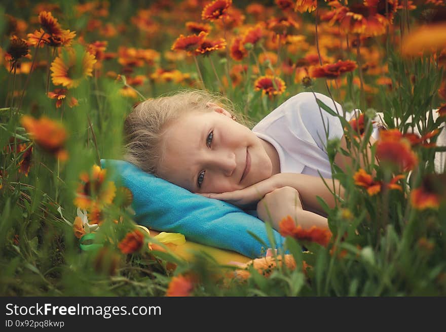 A happy child is relaxing outdoors in nature . Girl laying among the flowers