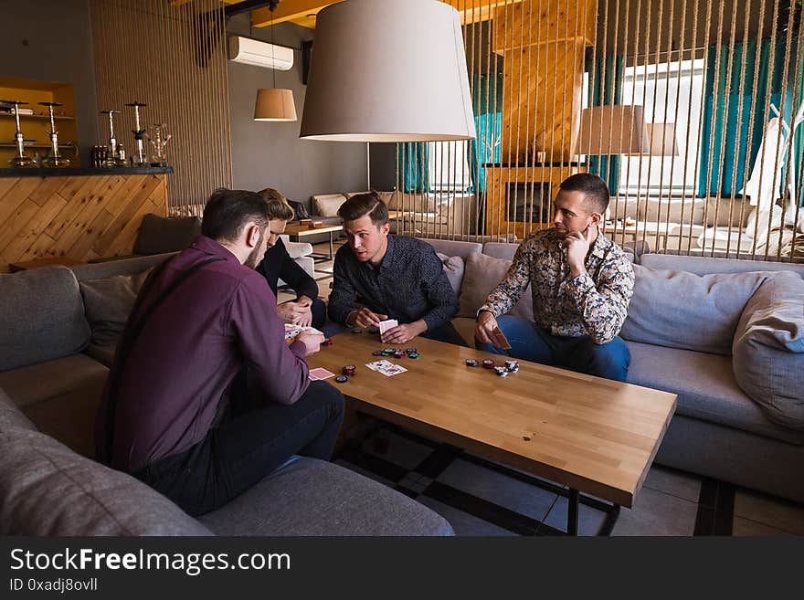 Several men are playing poker in a cafe, holding cards in their hands