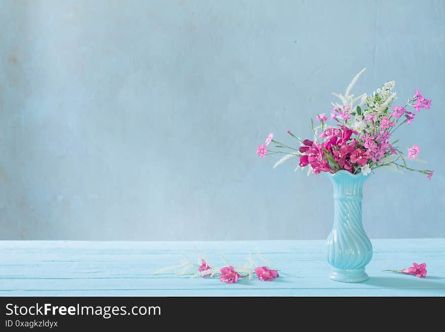 pink flowers in vase on blue background