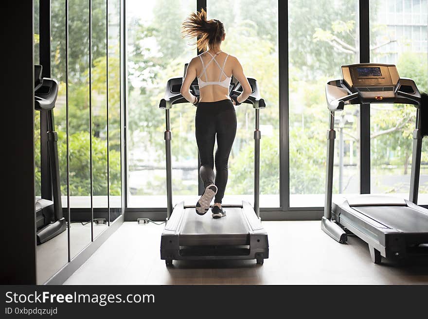 A Beautiful asian sport woman is running on treadmill in the gym