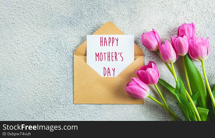 Mother`s day card. Pink tulips flowers and card with text on concrete background. Banner