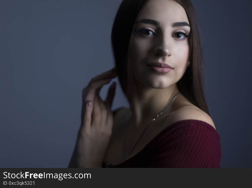 Art studio of a dramatic portrait of a young beautiful girl, with artistic retouching. Close-up, girl`s face, with an expressive look. On a dark background. Beauty portrait of a tender girl. Expressive facial features of a caucasian girl. Fashionable portrait of female beauty and health. Dark tones, shades, shadows