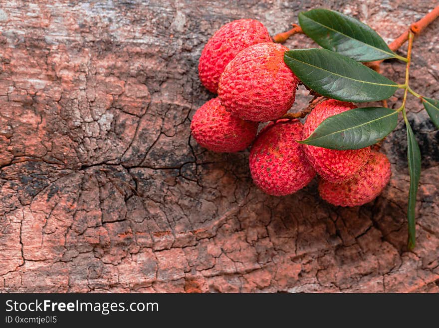 Lychee with leaves on wooden background. Tropical fruit, rustic style, cjpy space, close up. Lychee with leaves on wooden background. Tropical fruit, rustic style, cjpy space, close up