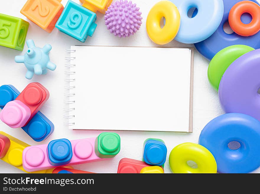 Baby toys and blank page notepad flat lay background with copy space. Toys list mockup