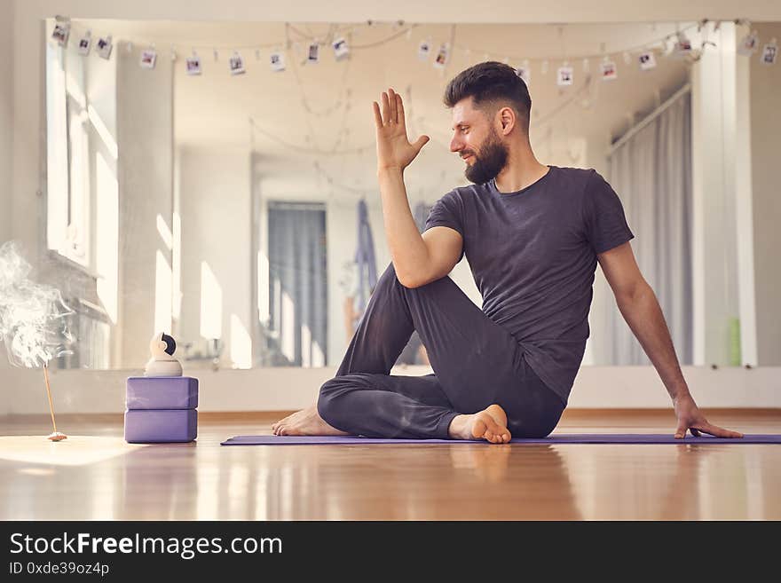 Bearded young man doing half lord of the fishes yoga pose