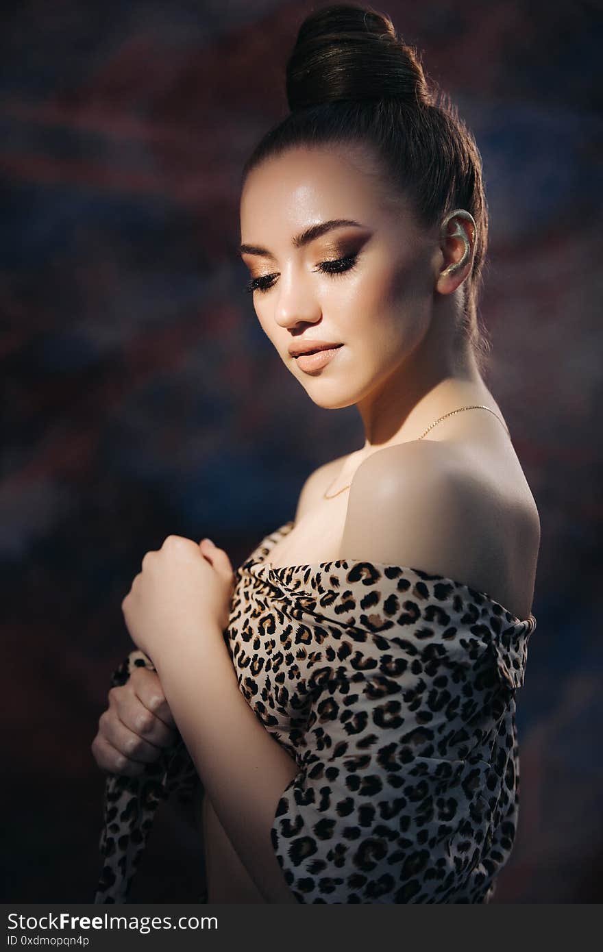 Beautiful stylish young girl in leopard print clothes. Fashionable clothes on a woman. Beautiful model with beautiful makeup and a high bun of hair