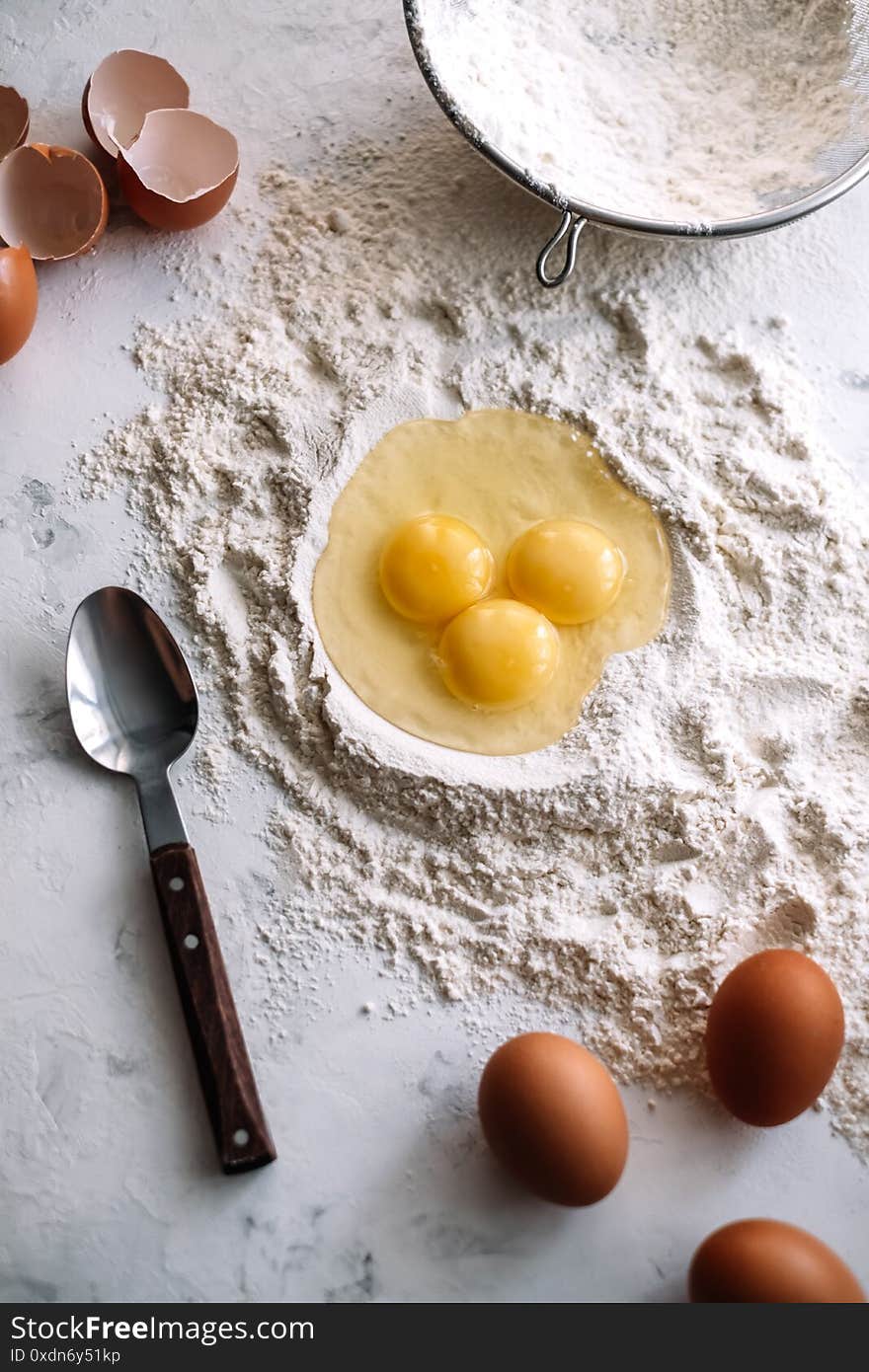 Chicken eggs in flour on the kitchen table, ingredients. Preparation for baking, culinary recipes. Top view. High quality photo