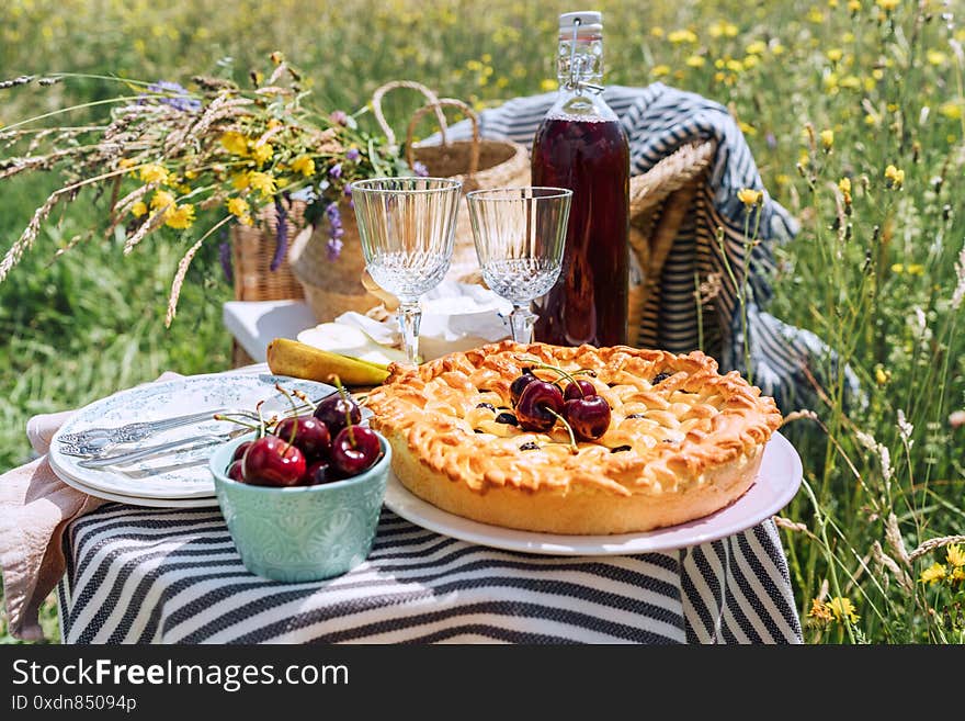 Table view served with beautiful vintage wine glasses, plates, silver cutlery and tableware, tablecloth, sweet cherry pie and fresh cherries still life. Homemade baking and recipes illustration