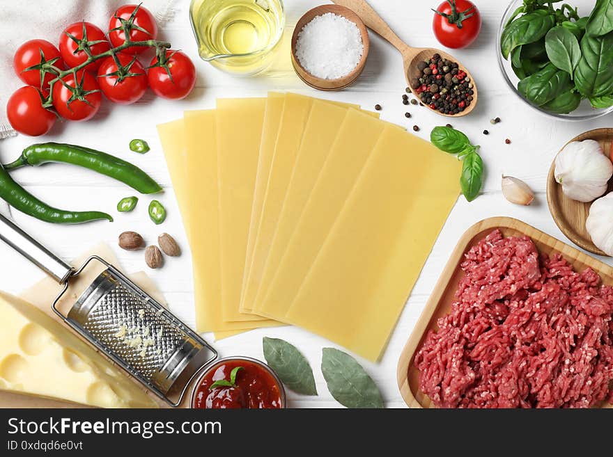 Fresh ingredients for lasagna on white wooden table, flat lay