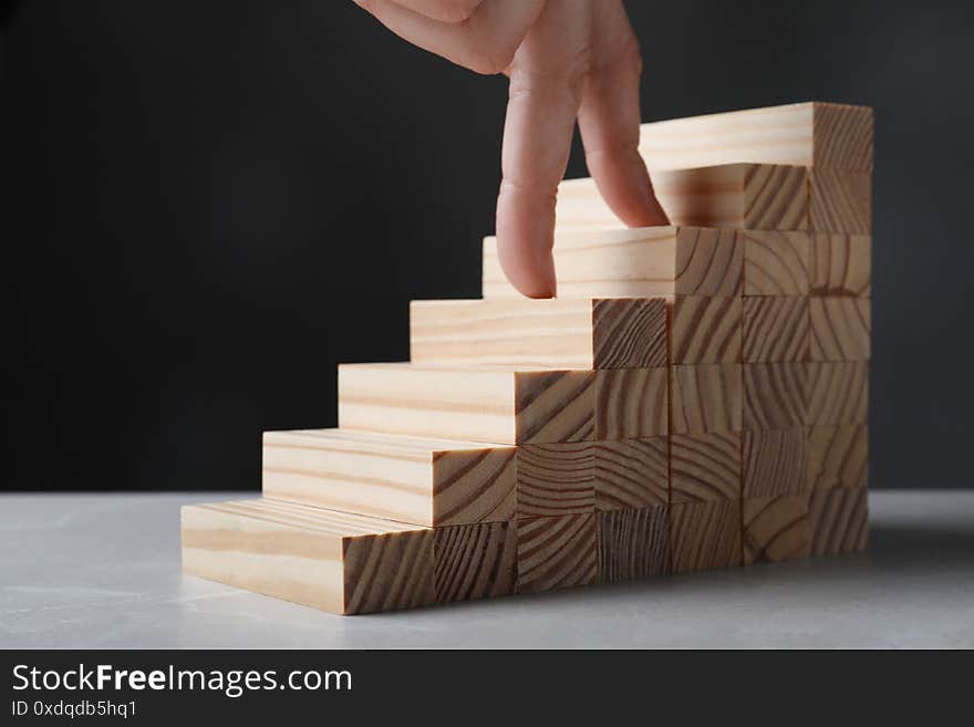 Woman imitating stepping up on wooden stairs with her fingers, closeup. Career ladder