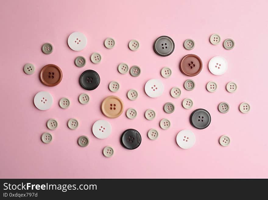 Many sewing buttons on pink background, flat lay