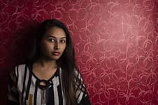 Fashion Portrait Of An Indian Bengali Beautiful And Young Girl In Western Dress Standing In Front Of A Red Textured Wall. Stock Photos