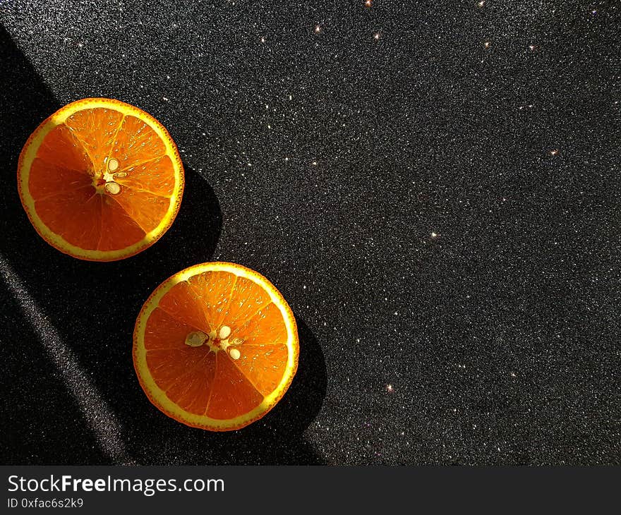 Orange is bright juicy on a black shiny background. Place for the buyer`s text. A clear shadow passing through the middle of the orange slices. High quality photo