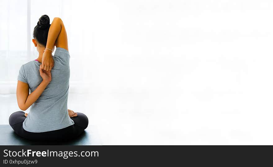 Female doing stretching exercises yoga. Hands behind back, sitting in Vajrasana pose with hands hooked behind the back.