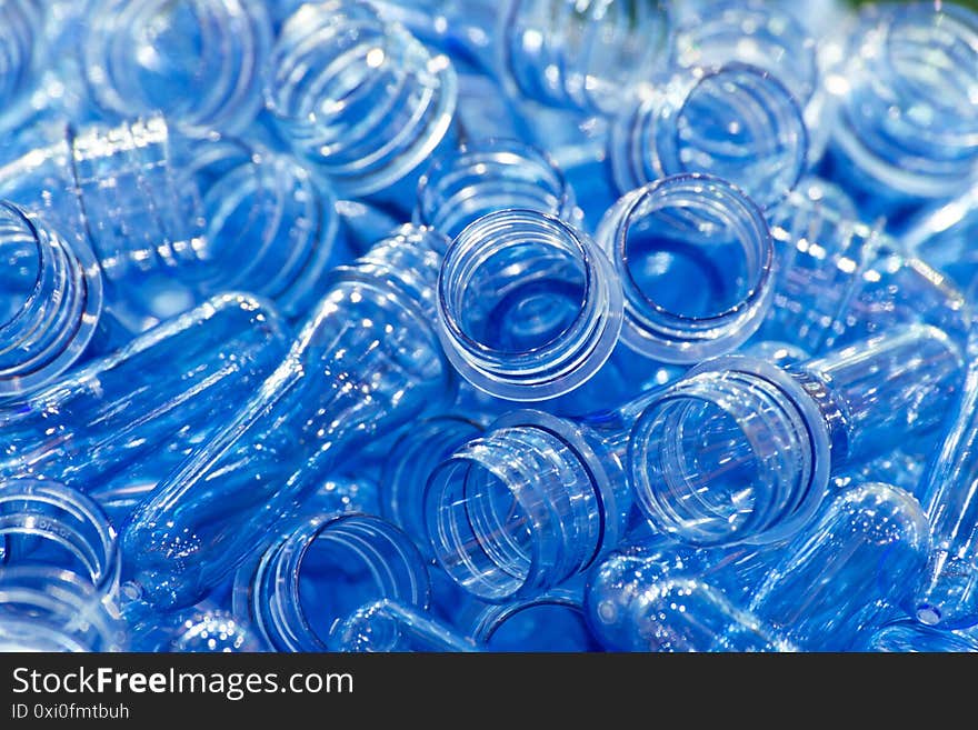 Group of blue transparent plastic PET preforms is ready to produce for water drink packaging plastic bottle in the beverage