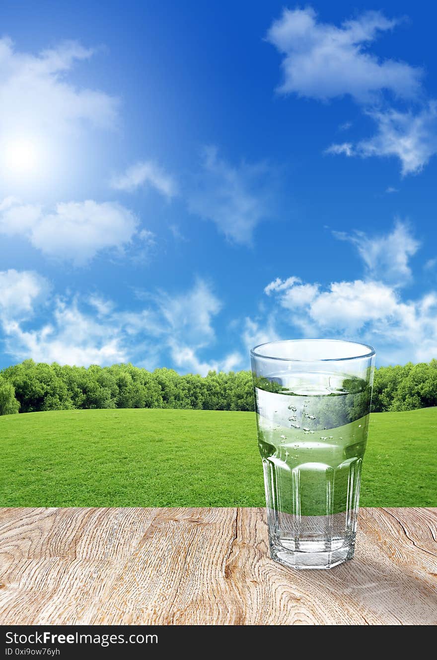 Glass of water on wood table and blue sky