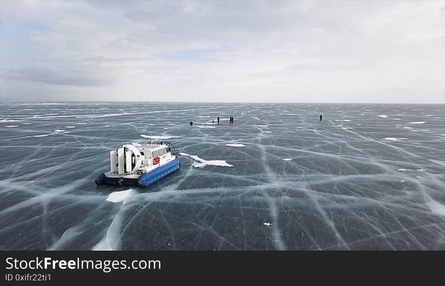 Aerial view of the machine moving on the frozen amazing lake. Typical hovercraft vehicle on clear craked ice surface, Lake Baikal, Siberia, Russia. Aerial view of the machine moving on the frozen amazing lake. Typical hovercraft vehicle on clear craked ice surface, Lake Baikal, Siberia, Russia.