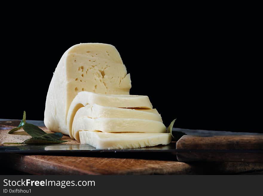 Sliced Cheese And Knife On The Old Wooden Board With Black Background