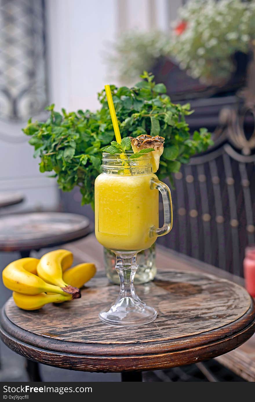 Cool smoothie with pineapple, mango, banana and mint on wooden background