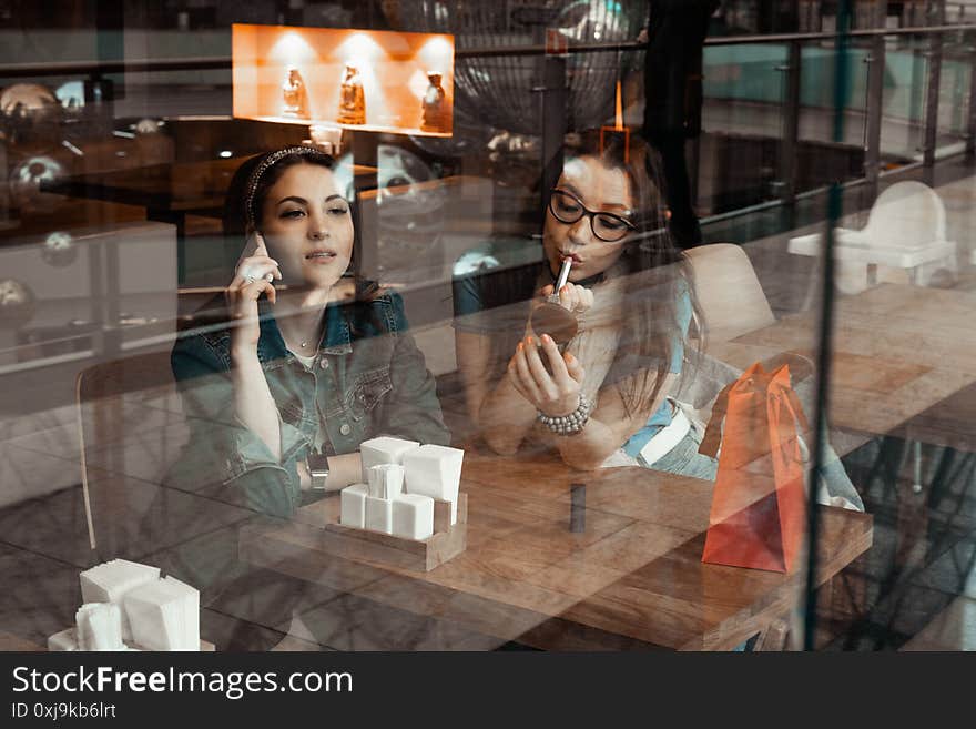 Cafes and bars. Two girls are sitting at a cafe table. Discussion of shopping. Girlfriends in a cafe.