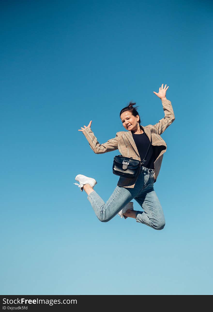 Jump In The Air. A Girl In Full Height Jumps In The Air Having Fun On A Bright Blue Turquoise Background Of The Summer Sky Color.