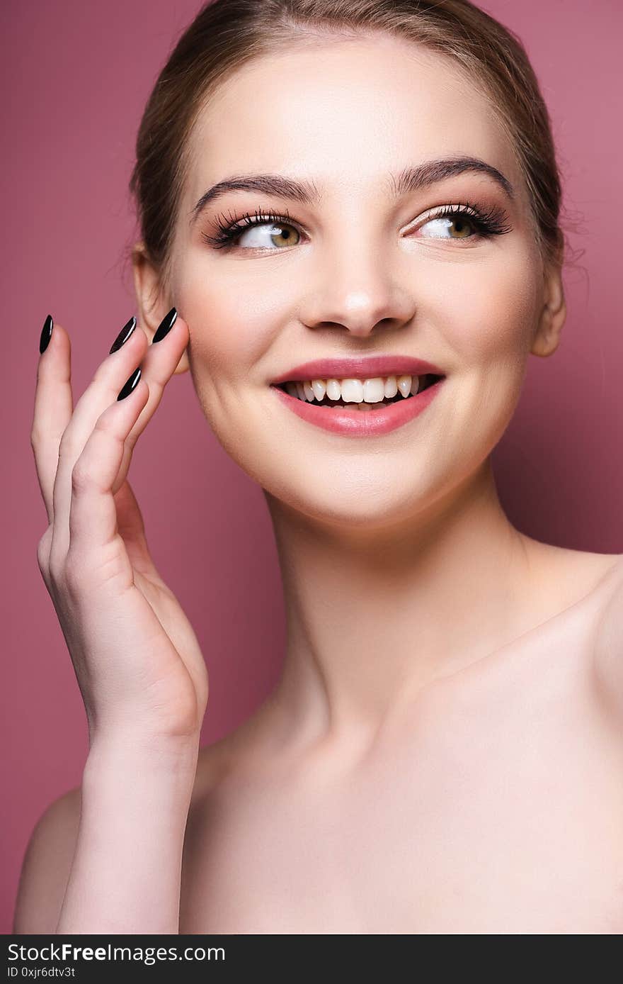 woman with eye shadow and lipstick touching face and smiling on pink. woman with eye shadow and lipstick touching face and smiling on pink