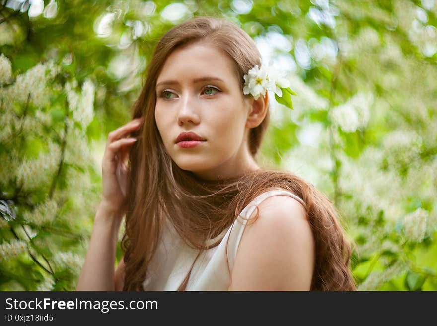 Portrait of woman on a background of blooming apple tree.