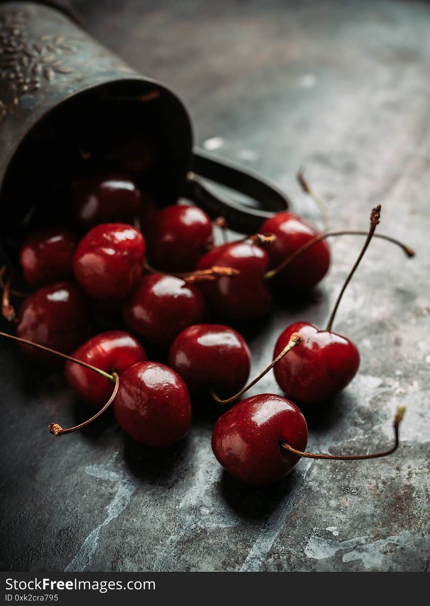 Freshly harvested cherries in vintage metal cup. Selective focus. Shallow depth of field.