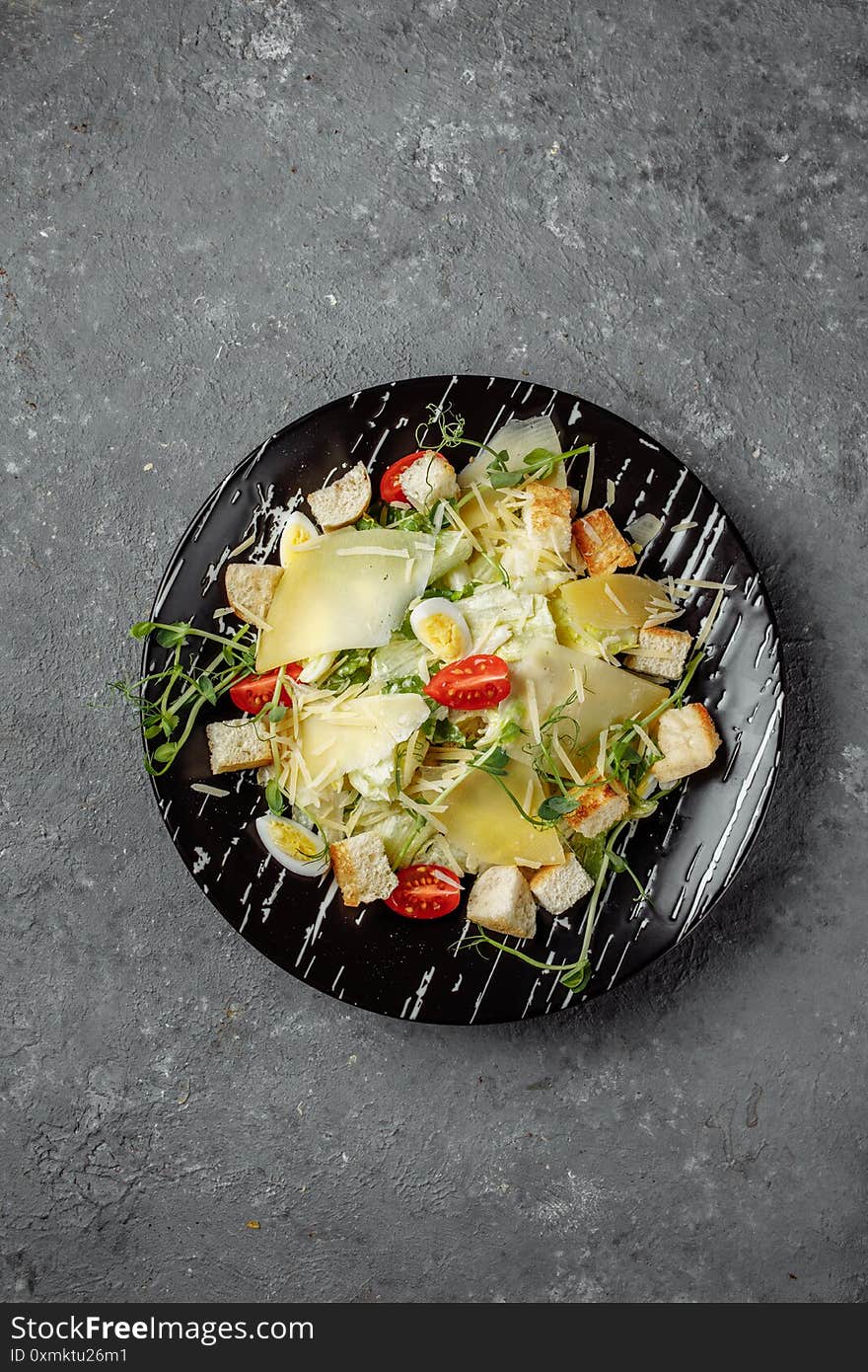 Fresh Caesar Salad In A Black Plate On A Gray Background.Top View