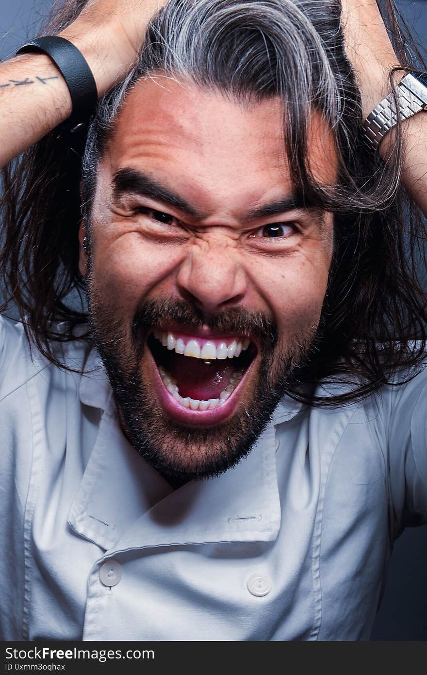 Vertical Shot Of A Screaming Male Standing In Front Of A Gray Wall - Concept Of Emotions