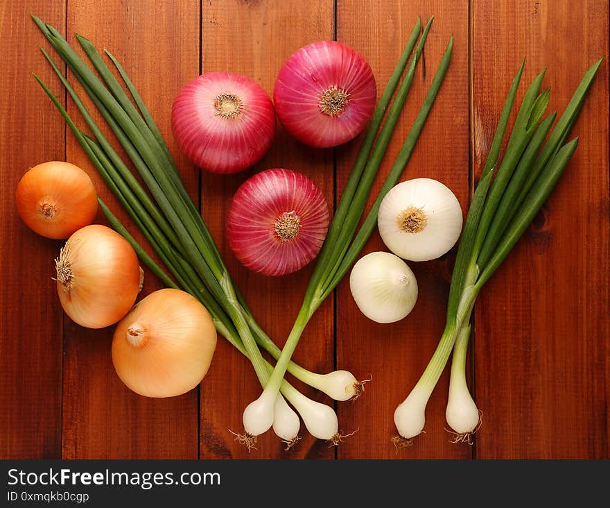 Assorted beautiful, different onions on a wooden background