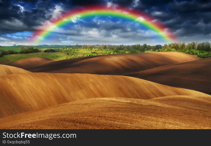 Rainbow over a picturesque hilly field