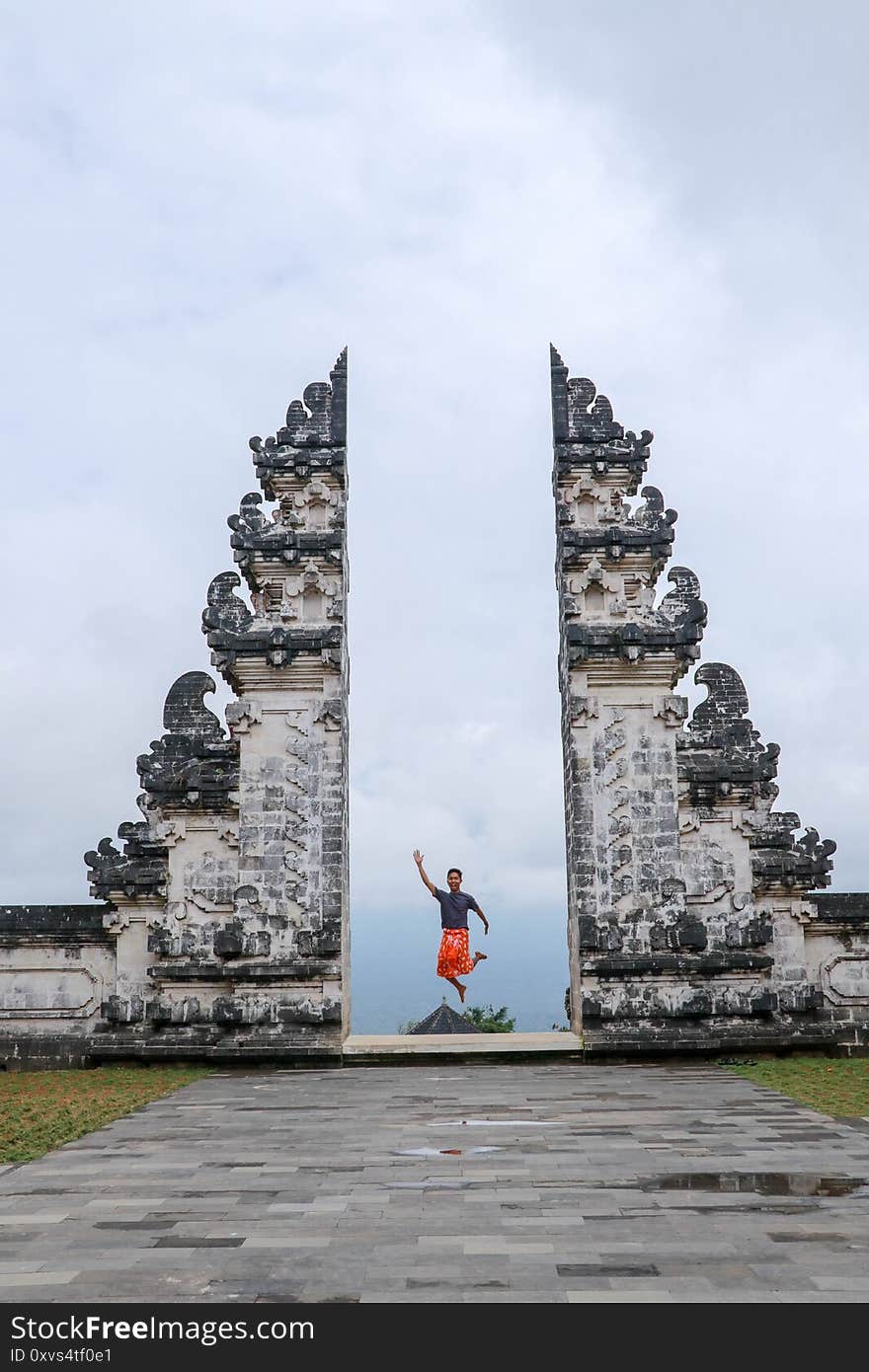 Bali, Indonesia. Young taveler man jumping with energy and happiness in the gate of heaven. Lempuyang temple.