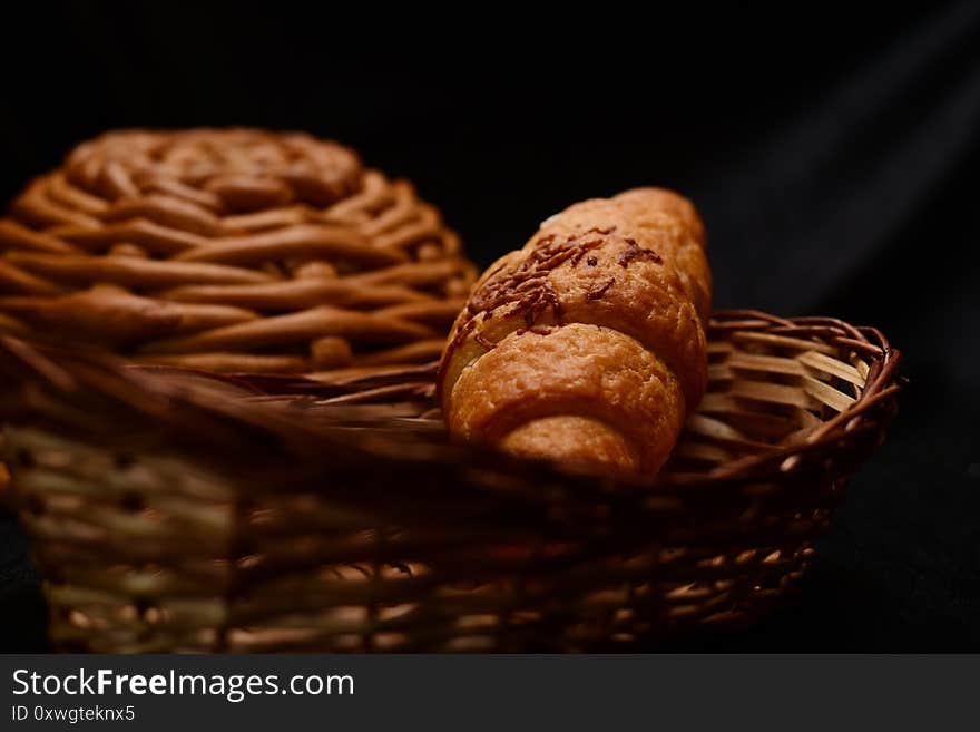 Bread roll in wicker basket isolated black background