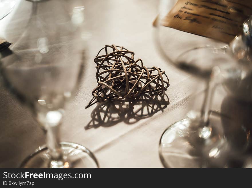 Closeup Of Table Decoration. Art Object, Wicker Heart Shape. Shadow On White Table Cloth. Celebration, Birthday, Wedding