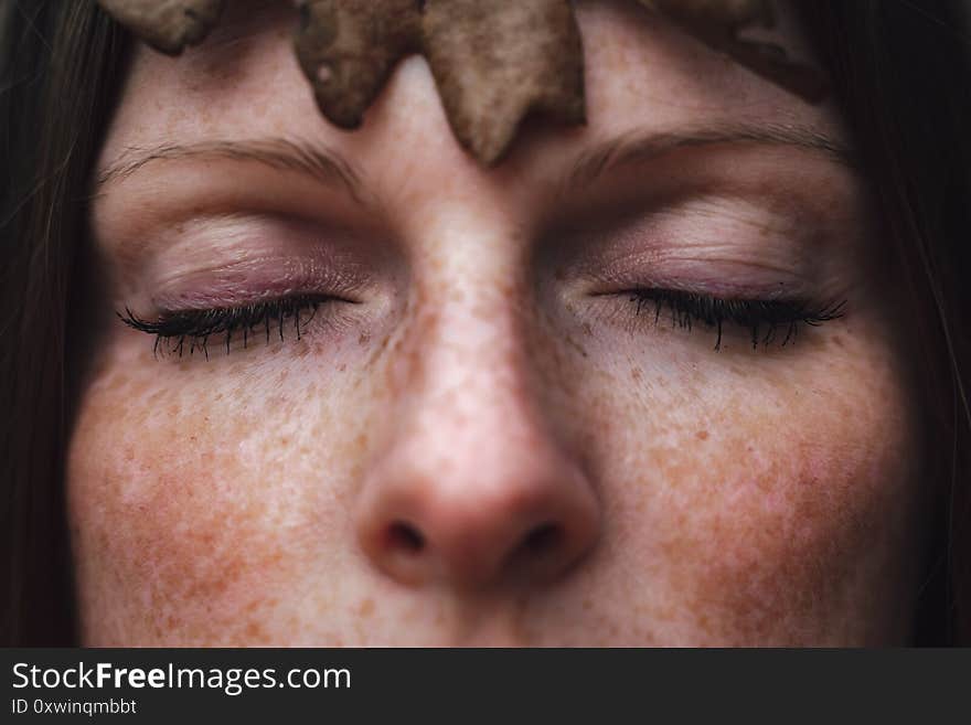 Closed eyes of young woman with leaf in autumn