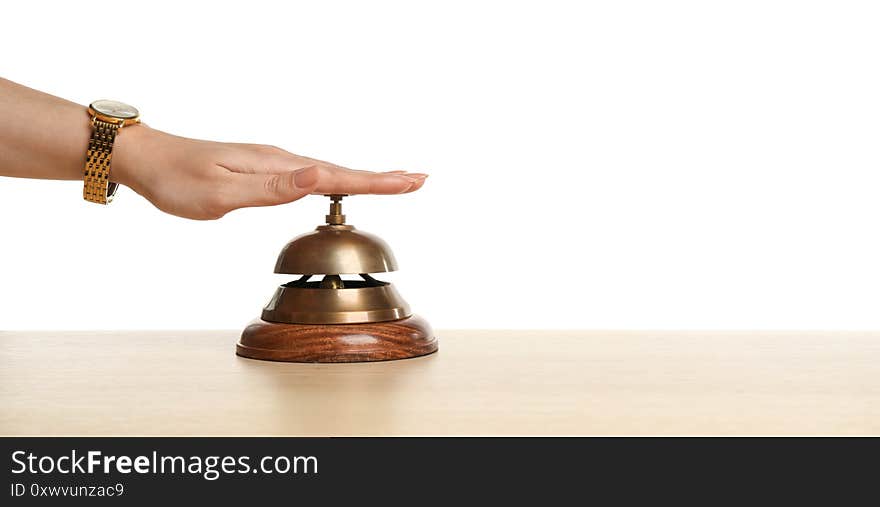 Woman ringing hotel service bell at wooden table