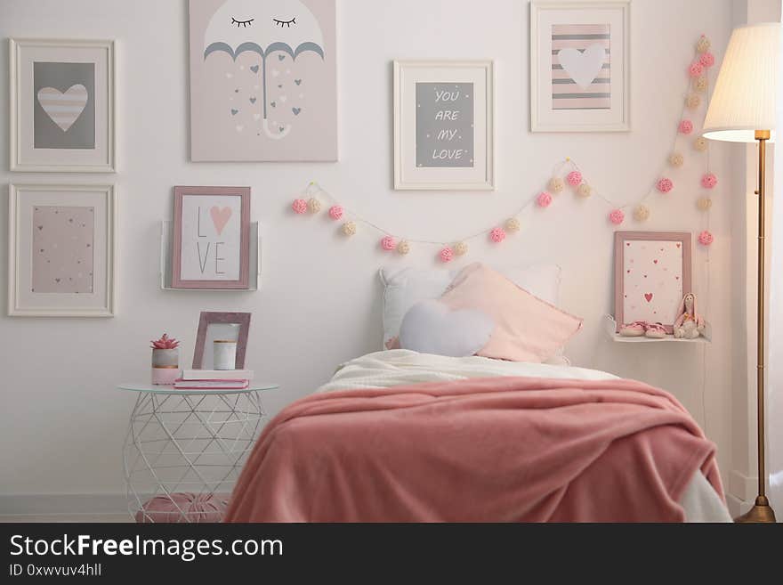 Stylish child`s room interior with beautiful pictures and comfortable bed