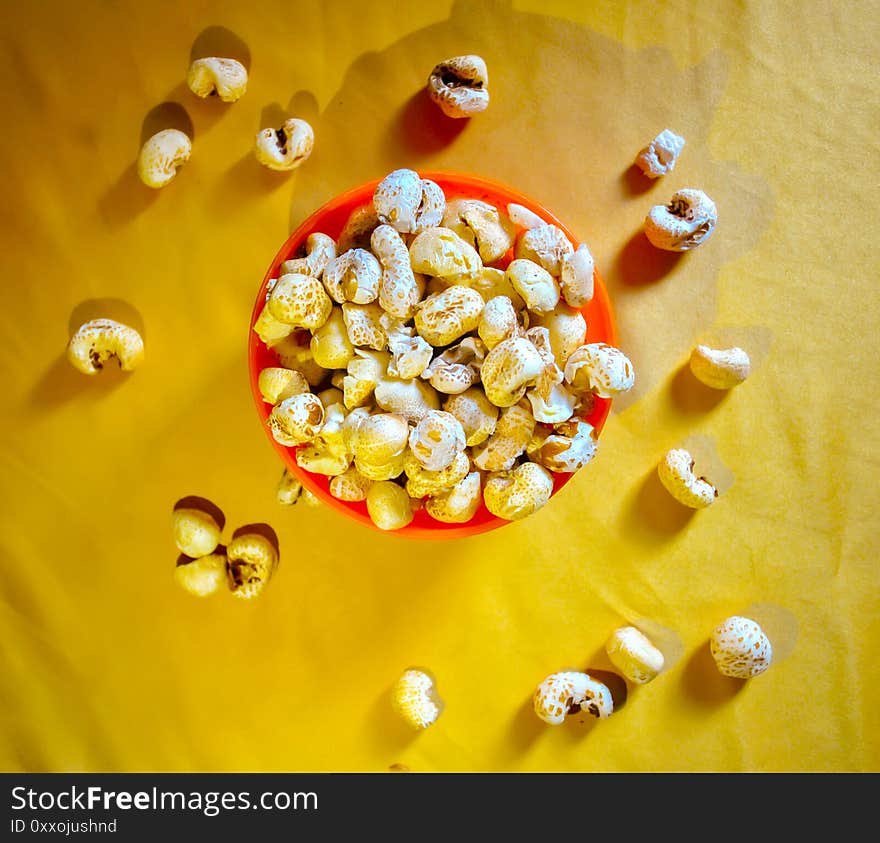 Popcorn in an orange bowl on yellow background