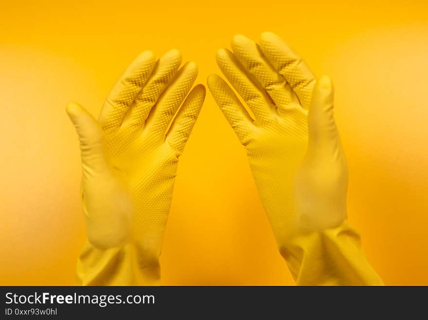 Hands in yellow gloves on a yellow background