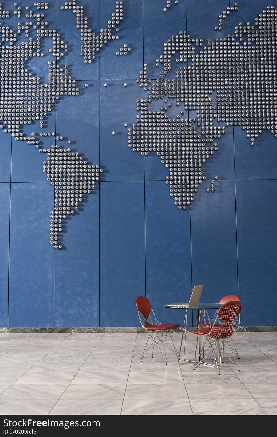 Laptop on table in empty office with world map on wall