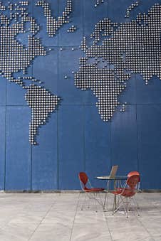 Laptop On Table In Empty Office With World Map On Wall Royalty Free Stock Image