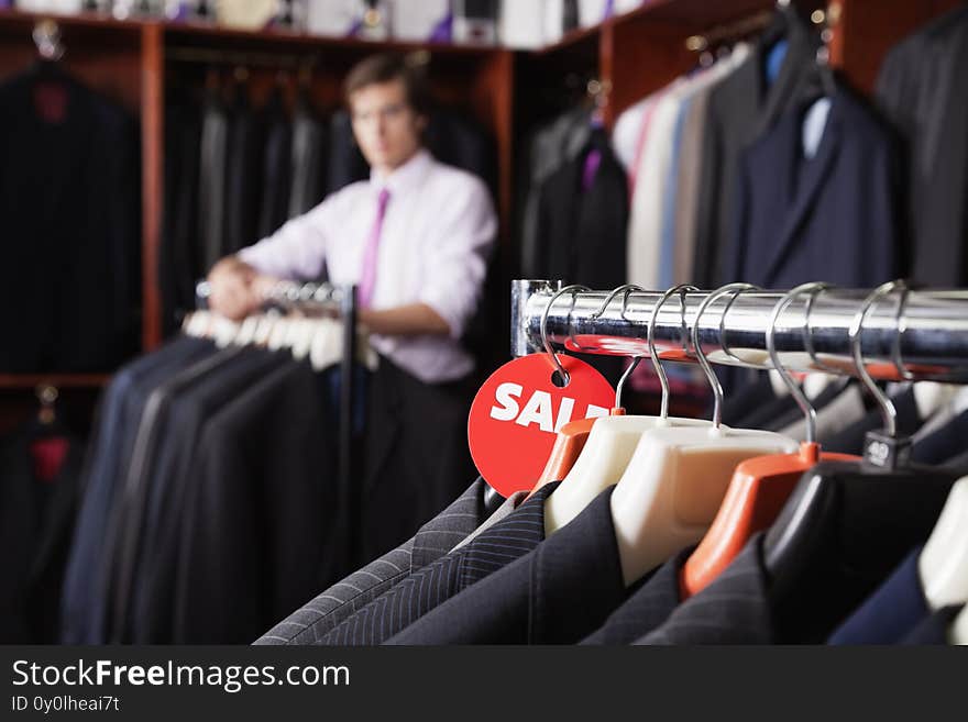 Close-up photo of suits hanging on rack with price tag in store