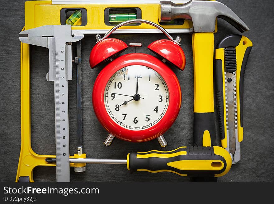 Red alarm clock and work tools on the table. Repair time abstract background. Red alarm clock and work tools on the table. Repair time abstract background