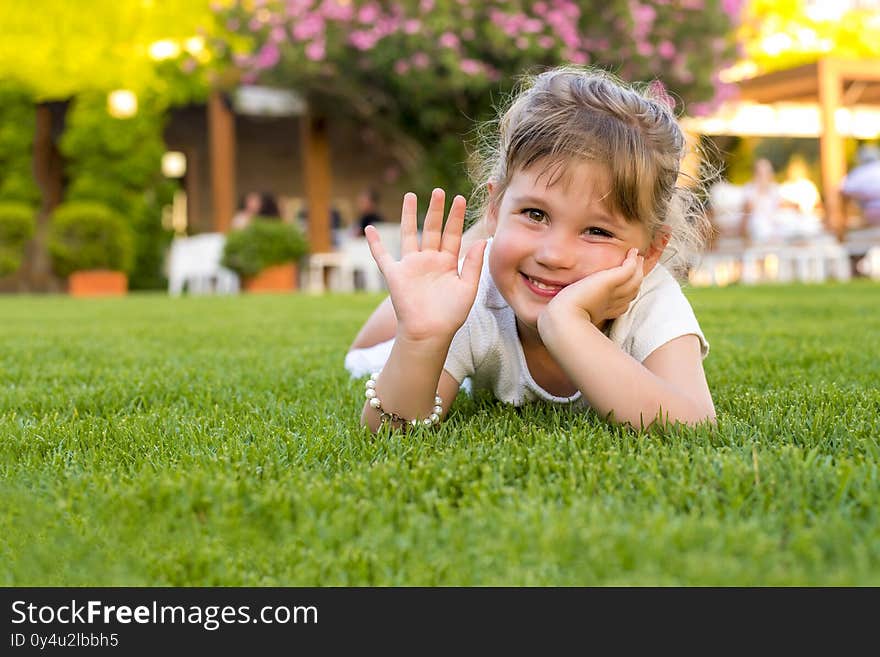 Shallow focus shot of a young female lying on green grass and smiling at camera