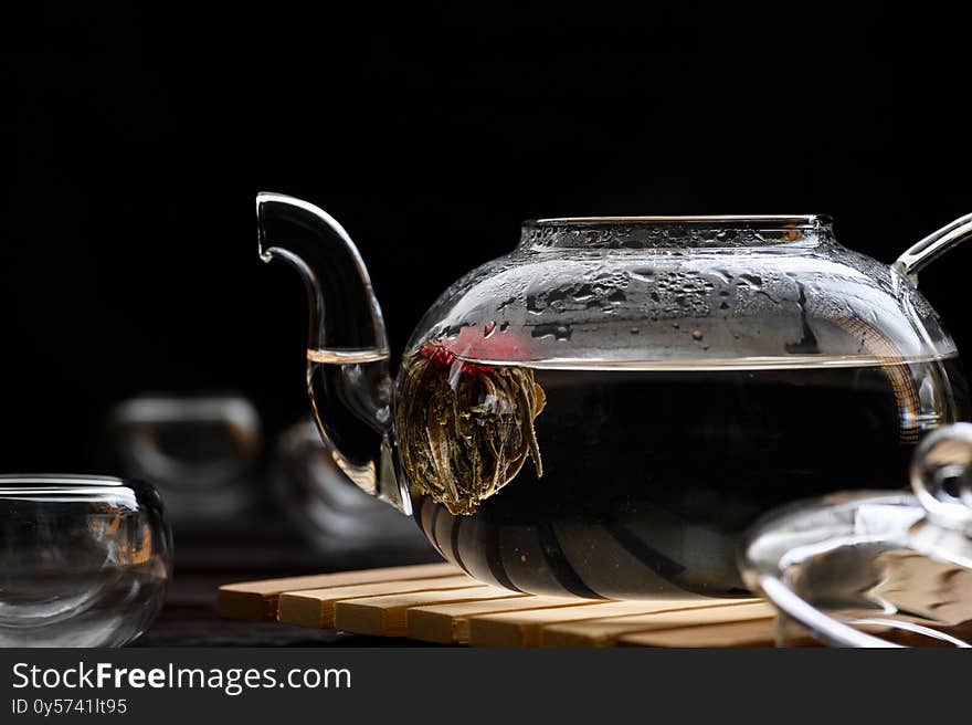 Teapot and glass cup with blooming tea flower